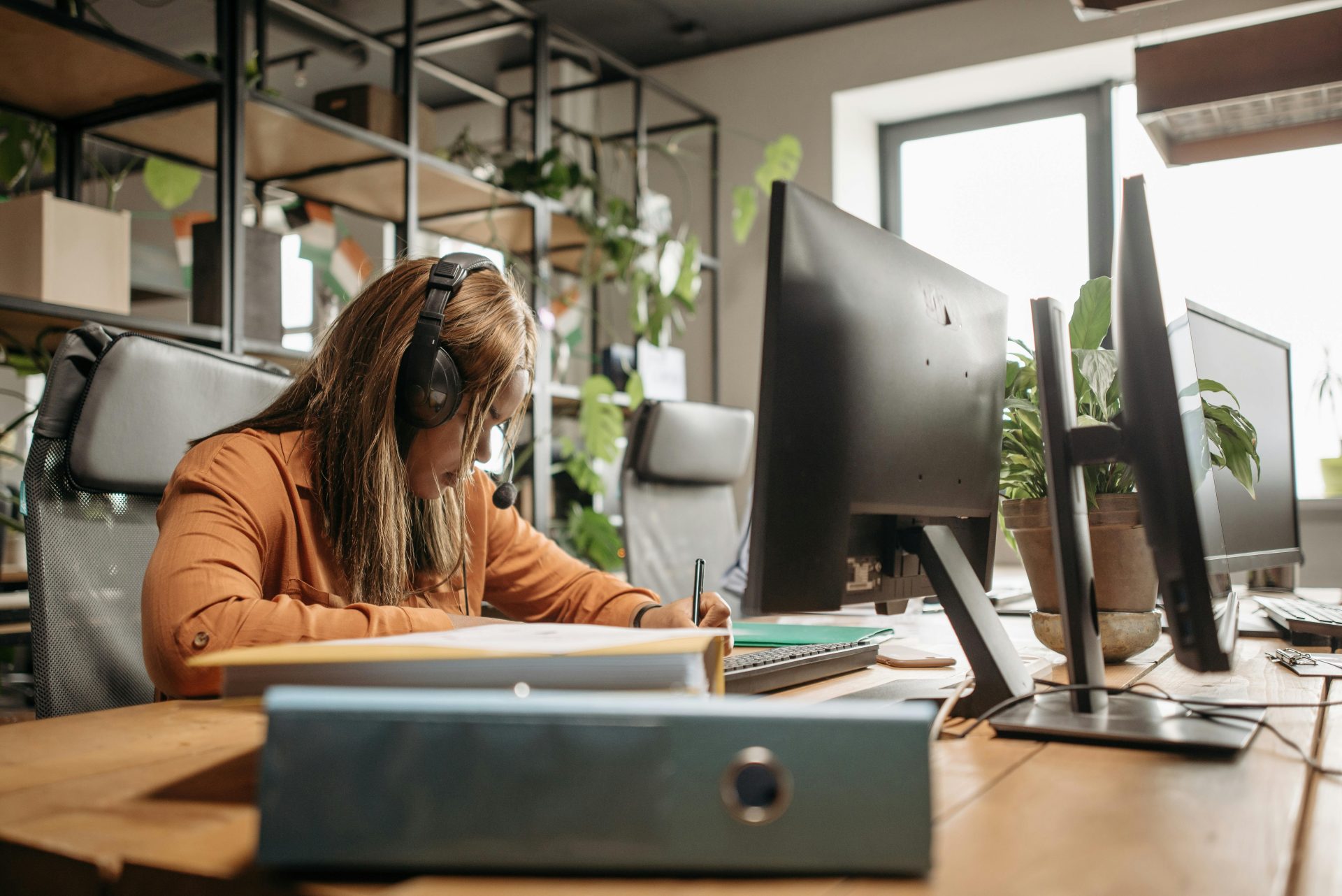 Konzentrierte Frau mit Headset arbeitet in einem modernen Büroumfeld.